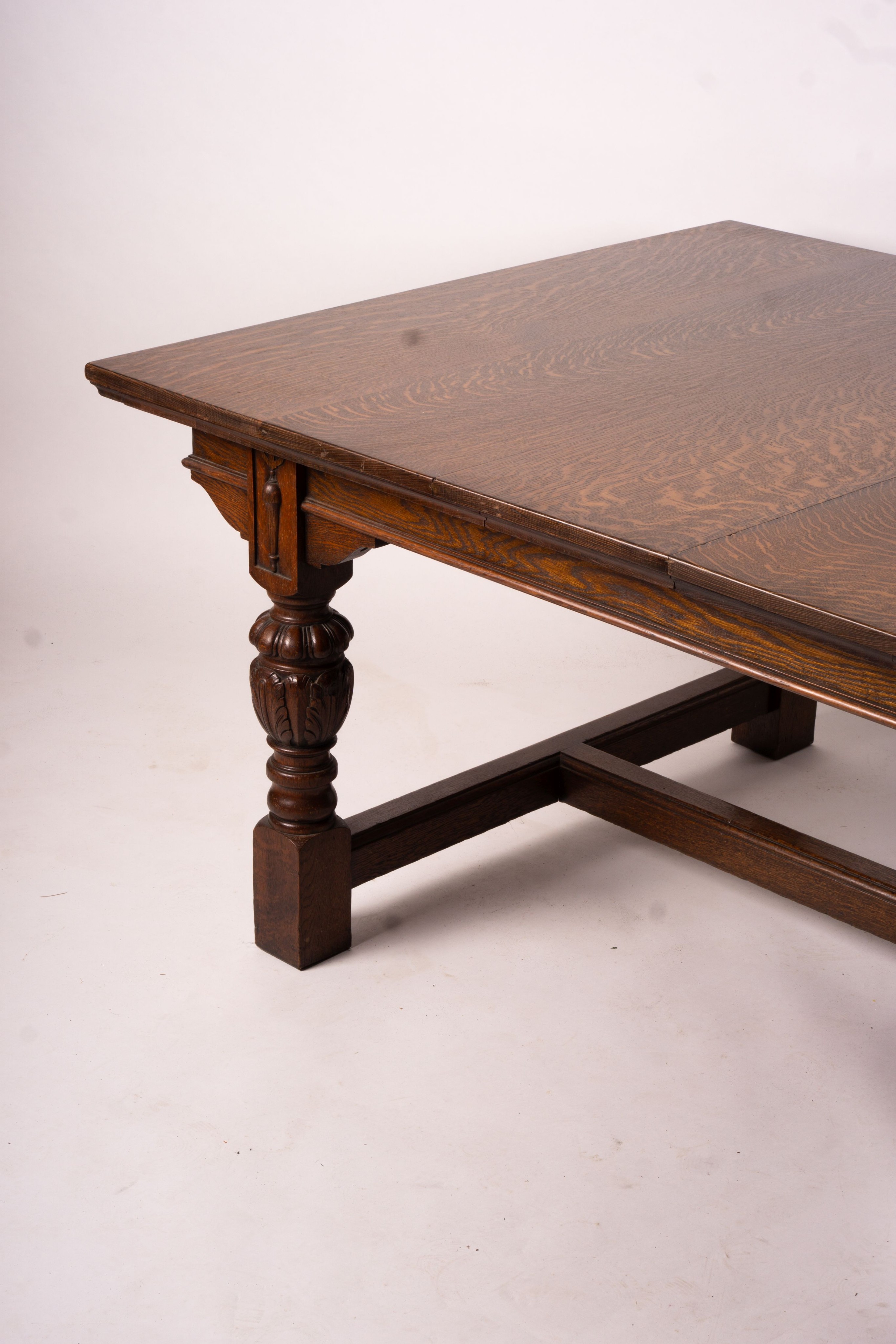 A 17th century style carved rectangular oak extending dining table with 'H' stretcher, 300cm extended, two spare leaves, width 121cm, height 75cm